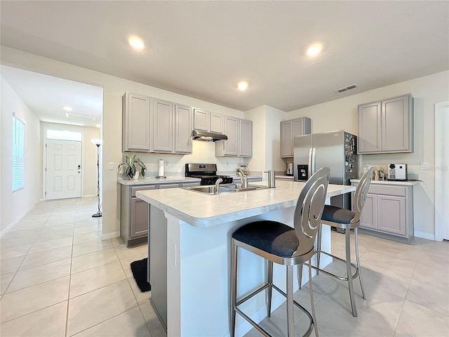 kitchen with gray cabinetry, sink, a kitchen bar, a center island with sink, and appliances with stainless steel finishes