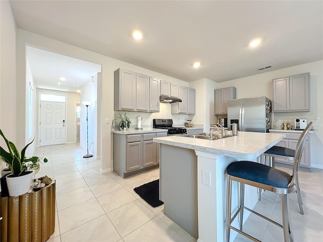 kitchen featuring a breakfast bar, sink, gray cabinetry, and stainless steel refrigerator with ice dispenser