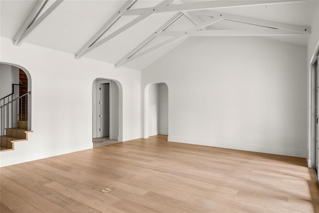 empty room with light hardwood / wood-style flooring, beamed ceiling, and high vaulted ceiling