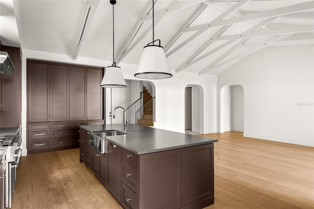 kitchen featuring sink, pendant lighting, lofted ceiling with beams, a center island with sink, and light hardwood / wood-style flooring