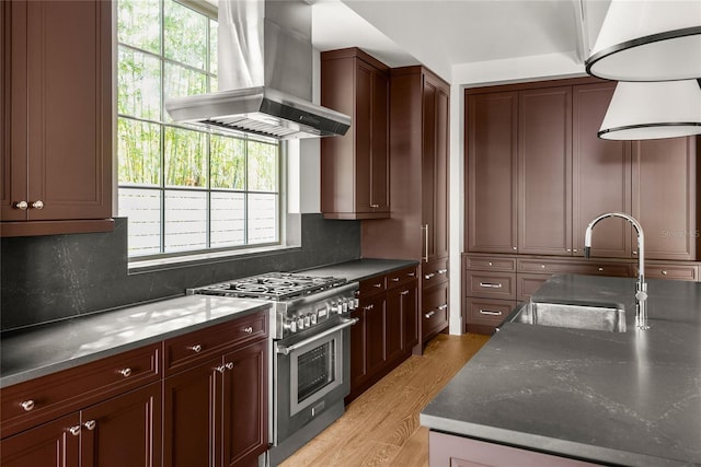 kitchen with light hardwood / wood-style floors, double oven range, island exhaust hood, and a wealth of natural light