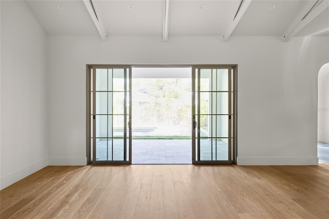 empty room with beam ceiling, light wood-type flooring, and a wealth of natural light