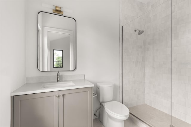 bathroom featuring toilet, vanity, and tiled shower