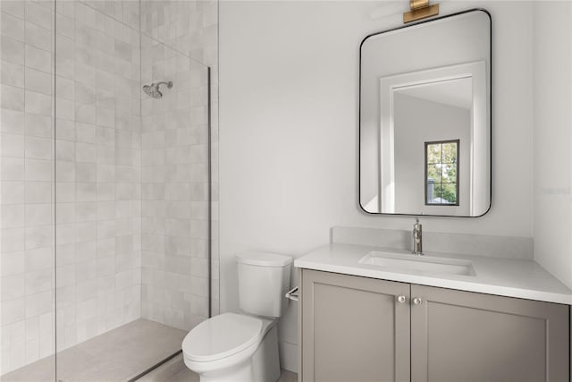 bathroom featuring vanity, toilet, and a tile shower