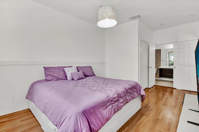 bedroom featuring connected bathroom and light hardwood / wood-style floors