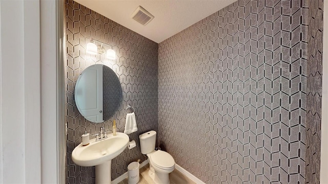 bathroom with toilet, tile walls, and sink