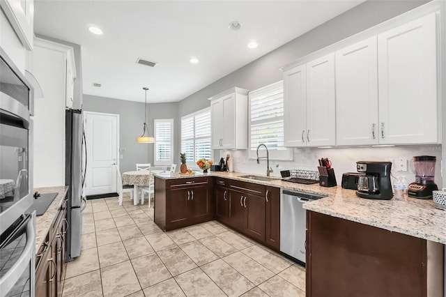 kitchen with white cabinets, sink, light tile patterned floors, appliances with stainless steel finishes, and decorative light fixtures