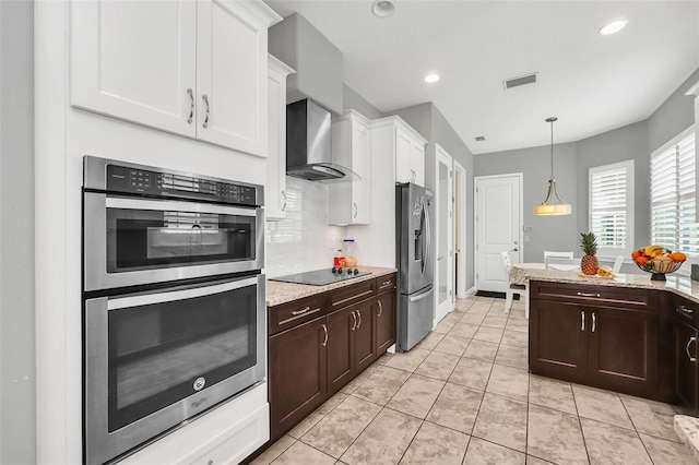 kitchen with white cabinets, wall chimney exhaust hood, dark brown cabinetry, and stainless steel appliances