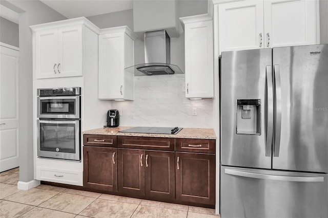 kitchen with decorative backsplash, stainless steel appliances, wall chimney range hood, white cabinetry, and light tile patterned flooring