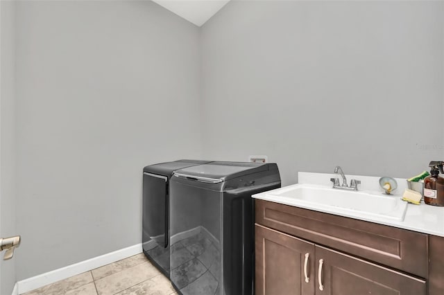 clothes washing area featuring light tile patterned flooring, cabinets, independent washer and dryer, and sink