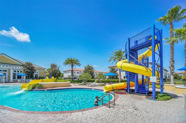 view of pool featuring a playground, a water slide, and a patio