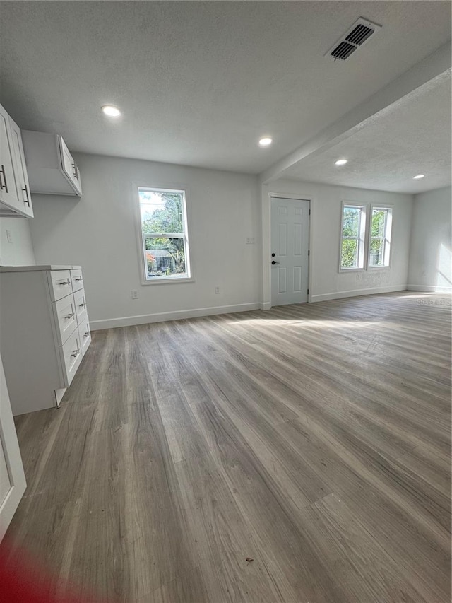 unfurnished living room with a textured ceiling, hardwood / wood-style flooring, and a wealth of natural light