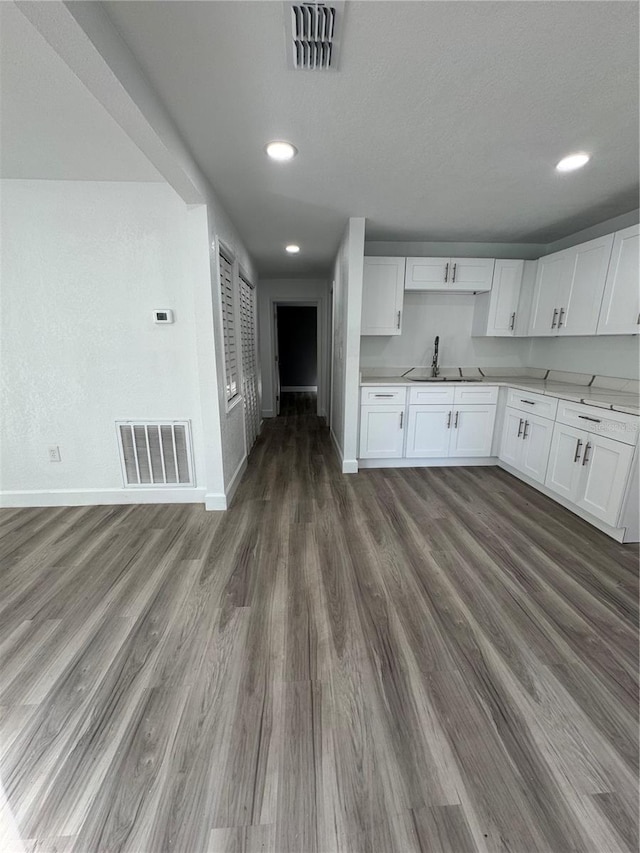 kitchen with white cabinets, a textured ceiling, dark hardwood / wood-style flooring, and sink