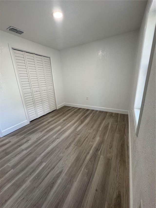 unfurnished bedroom featuring a closet and dark hardwood / wood-style flooring