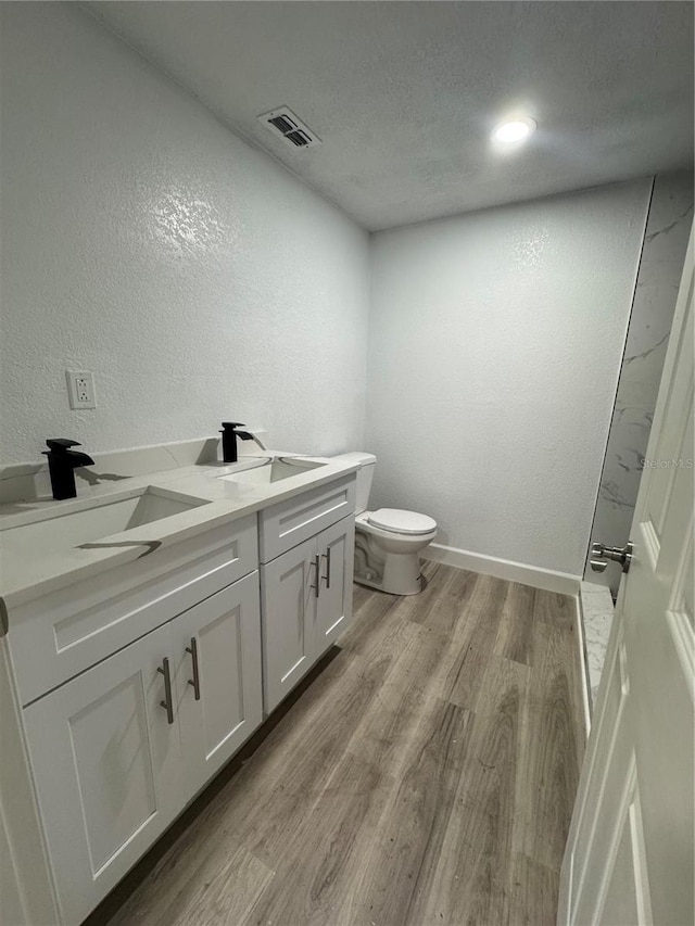 bathroom featuring vanity, a textured ceiling, a shower, wood-type flooring, and toilet