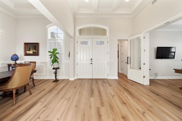 entryway with beamed ceiling, light wood-type flooring, crown molding, and a towering ceiling