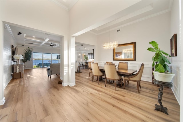 dining space with ceiling fan with notable chandelier, light hardwood / wood-style floors, ornamental molding, and coffered ceiling