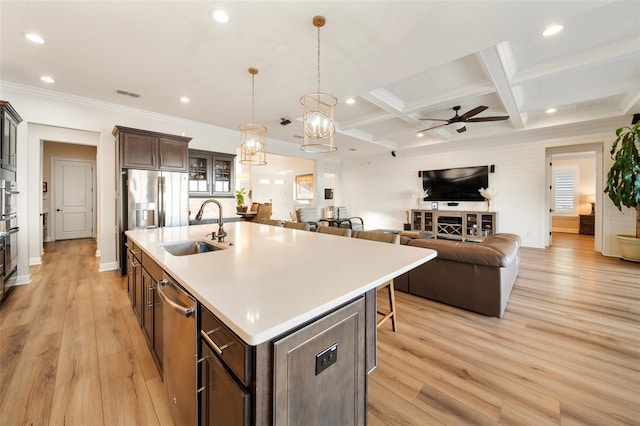 kitchen with pendant lighting, sink, an island with sink, and light hardwood / wood-style flooring