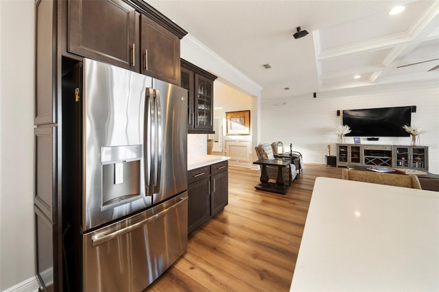 kitchen with stainless steel refrigerator with ice dispenser, ornamental molding, coffered ceiling, dark brown cabinetry, and light hardwood / wood-style floors