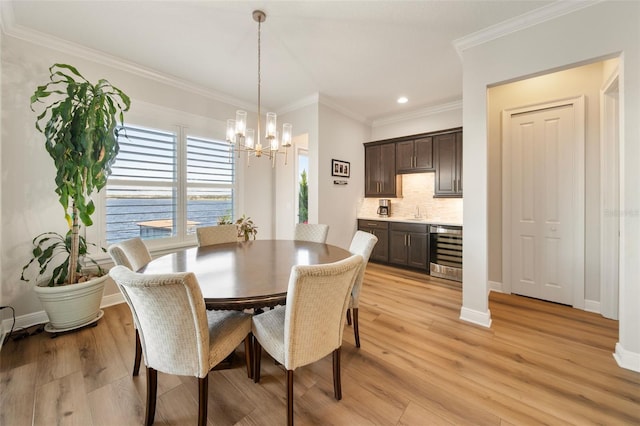 dining room featuring light hardwood / wood-style floors, ornamental molding, sink, and wine cooler