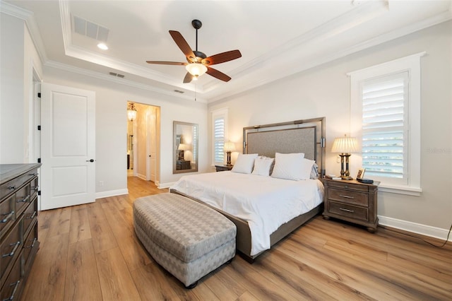 bedroom with light hardwood / wood-style floors, a raised ceiling, ceiling fan, and crown molding