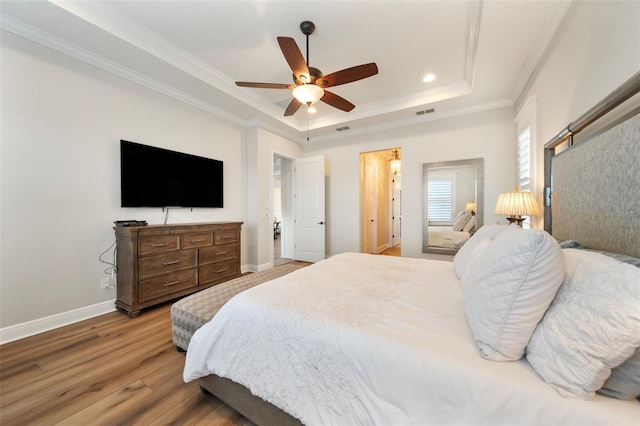 bedroom with wood-type flooring, a tray ceiling, ceiling fan, and crown molding