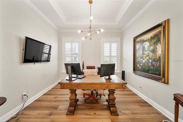 office space with light wood-type flooring, ornamental molding, and a tray ceiling