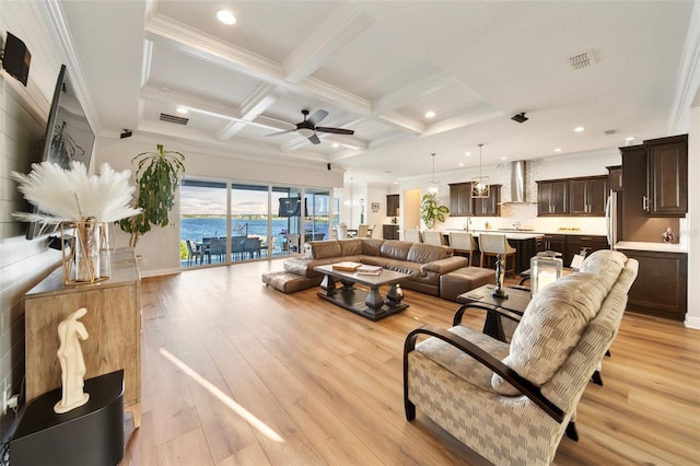 living room featuring beam ceiling, ceiling fan, crown molding, a water view, and light wood-type flooring