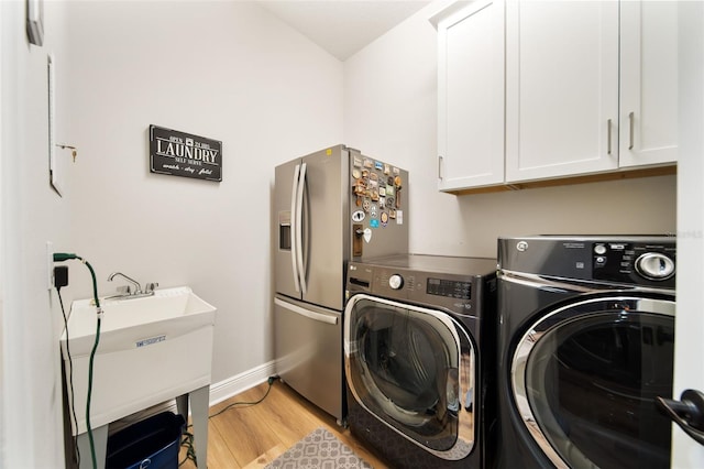 laundry area featuring washer and dryer, cabinets, and light hardwood / wood-style flooring