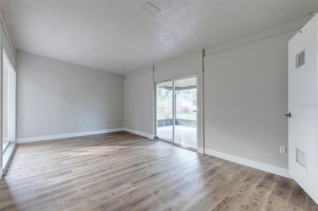 spare room with a textured ceiling and light wood-type flooring