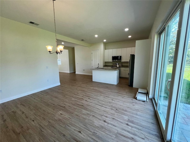 kitchen with pendant lighting, white cabinets, appliances with stainless steel finishes, and light hardwood / wood-style flooring