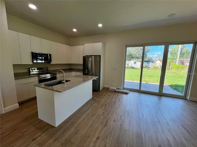 kitchen featuring a center island with sink, white cabinets, light wood-type flooring, and stainless steel appliances