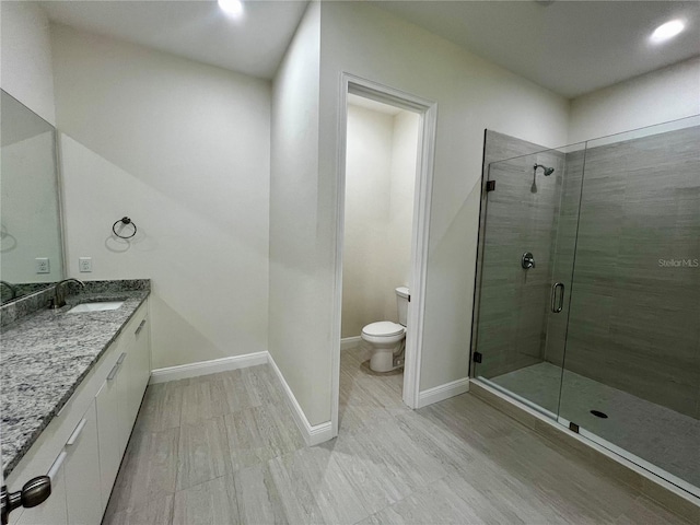 bathroom featuring a shower with door, vanity, hardwood / wood-style floors, and toilet