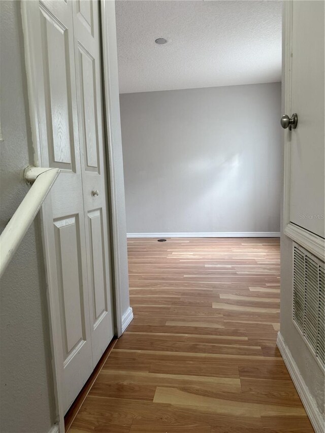 hallway featuring a textured ceiling and light wood-type flooring