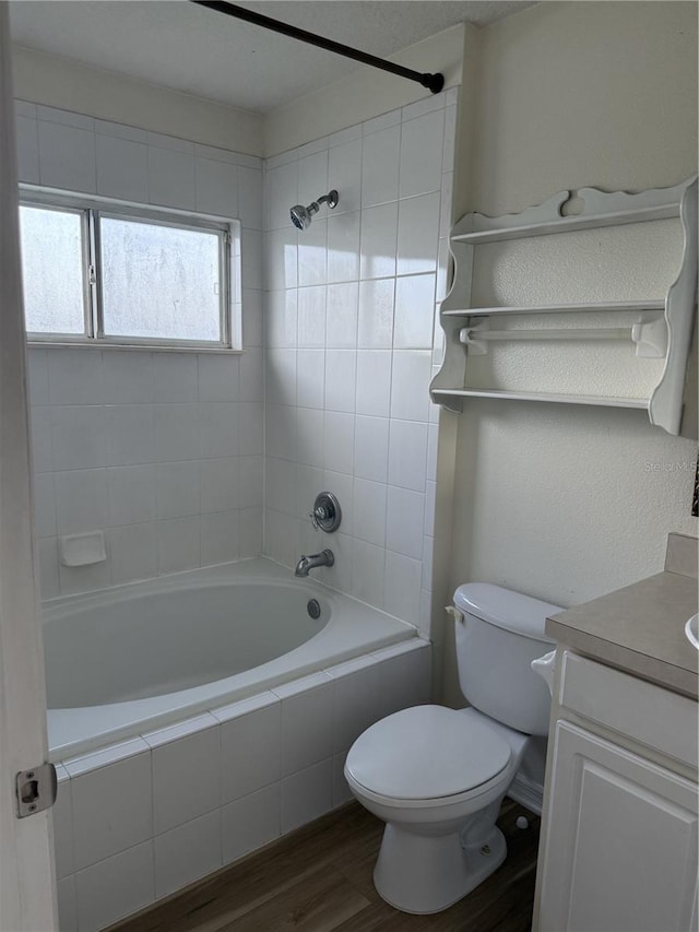 full bathroom featuring hardwood / wood-style flooring, vanity, toilet, and tiled shower / bath