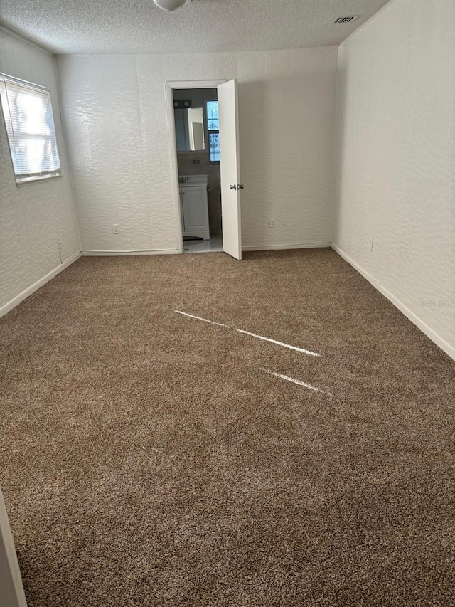 unfurnished room with carpet flooring and a textured ceiling