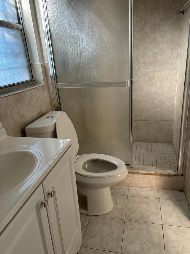 bathroom featuring tile patterned flooring, vanity, toilet, and a shower with door