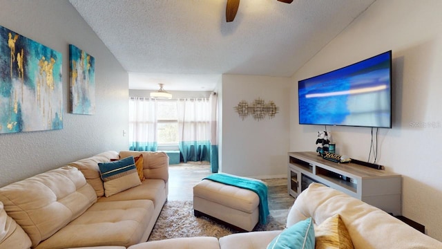 living room featuring a textured ceiling, light hardwood / wood-style floors, vaulted ceiling, and ceiling fan