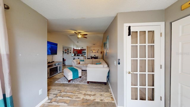 living room with a textured ceiling, vaulted ceiling, and ceiling fan