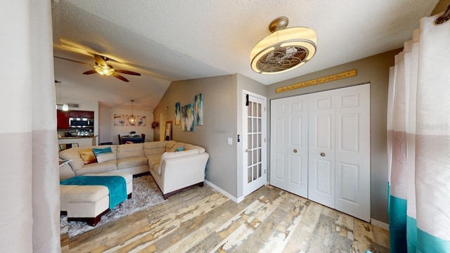 living room featuring a textured ceiling, ceiling fan, light hardwood / wood-style floors, and lofted ceiling