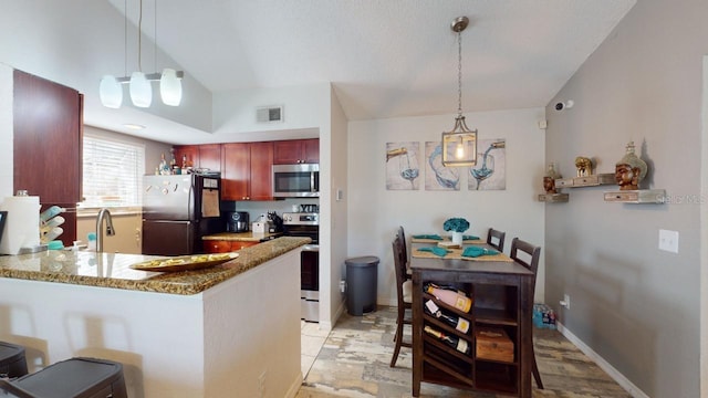 kitchen featuring kitchen peninsula, light stone countertops, decorative light fixtures, and appliances with stainless steel finishes