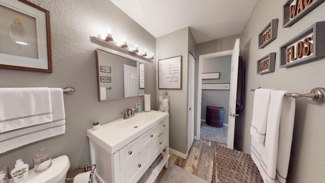 bathroom with hardwood / wood-style flooring, vanity, toilet, and a textured ceiling