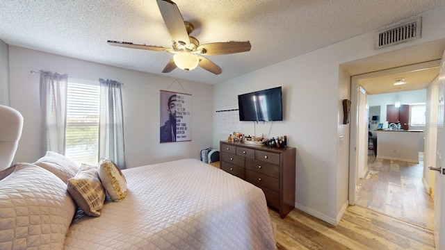 bedroom featuring ceiling fan, a textured ceiling, and light hardwood / wood-style flooring