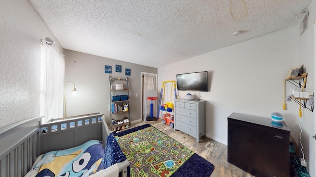 bedroom featuring lofted ceiling, light wood-type flooring, and a textured ceiling