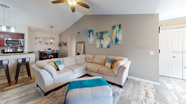 living room with ceiling fan, lofted ceiling, and light hardwood / wood-style flooring