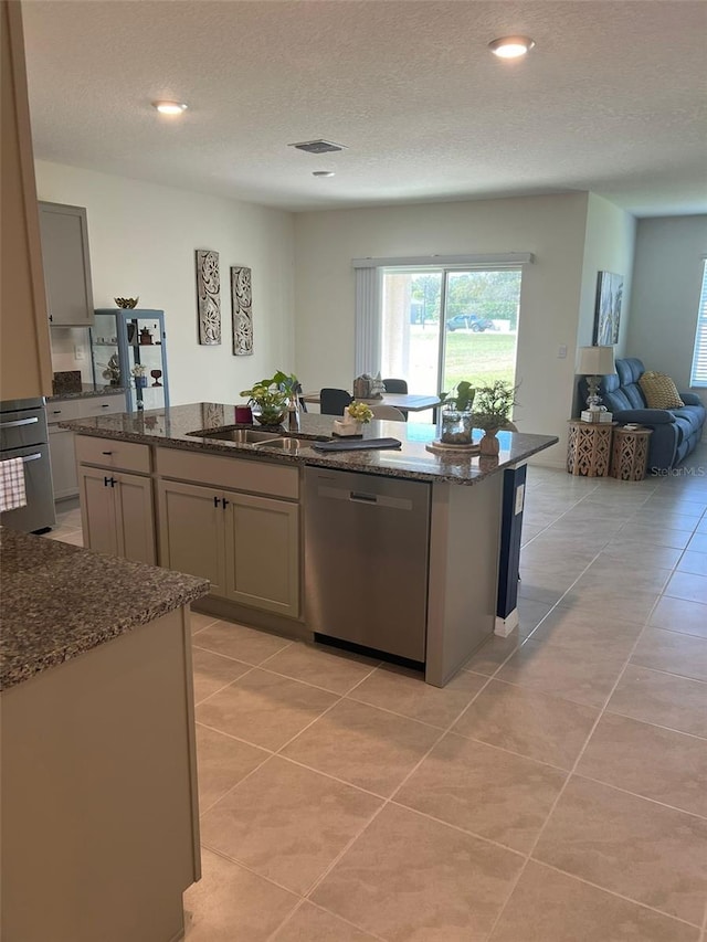 kitchen with dark stone counters, gray cabinetry, a center island, and stainless steel dishwasher