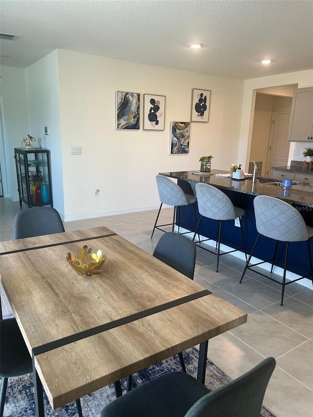 dining space featuring light tile patterned flooring and a textured ceiling