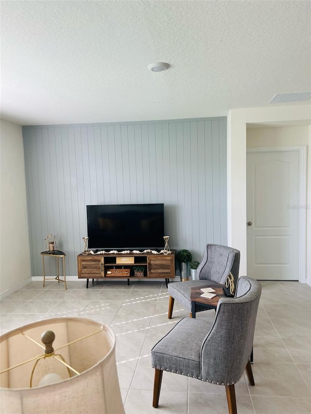 living area featuring tile patterned floors, visible vents, and a textured ceiling