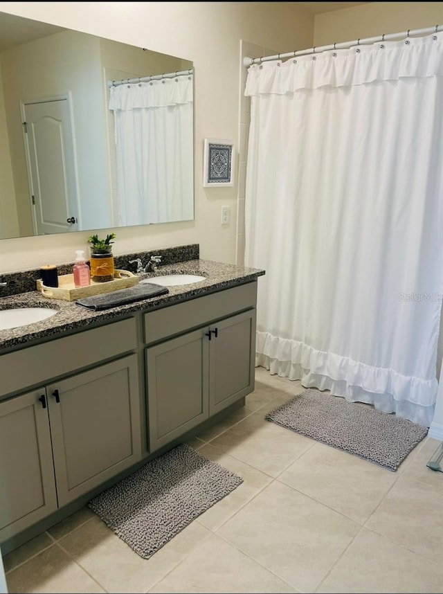 full bathroom with a sink, double vanity, and tile patterned floors