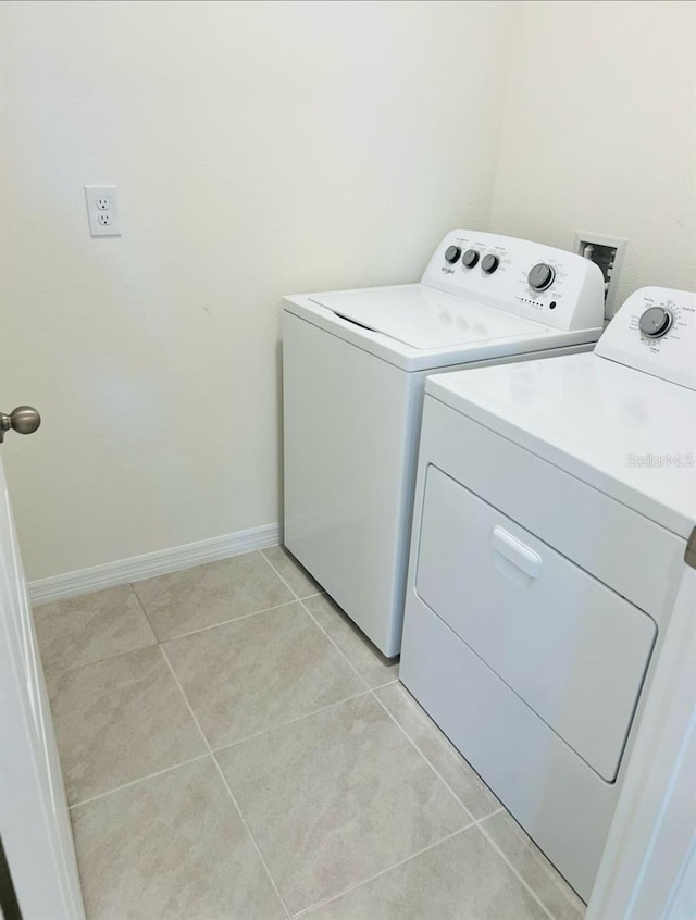 laundry area with light tile patterned floors, baseboards, separate washer and dryer, and laundry area